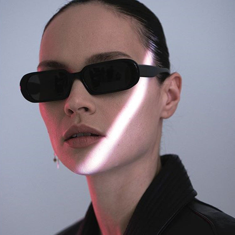Woman wearing retro small frame black sunglasses with a sleek design and dark lenses